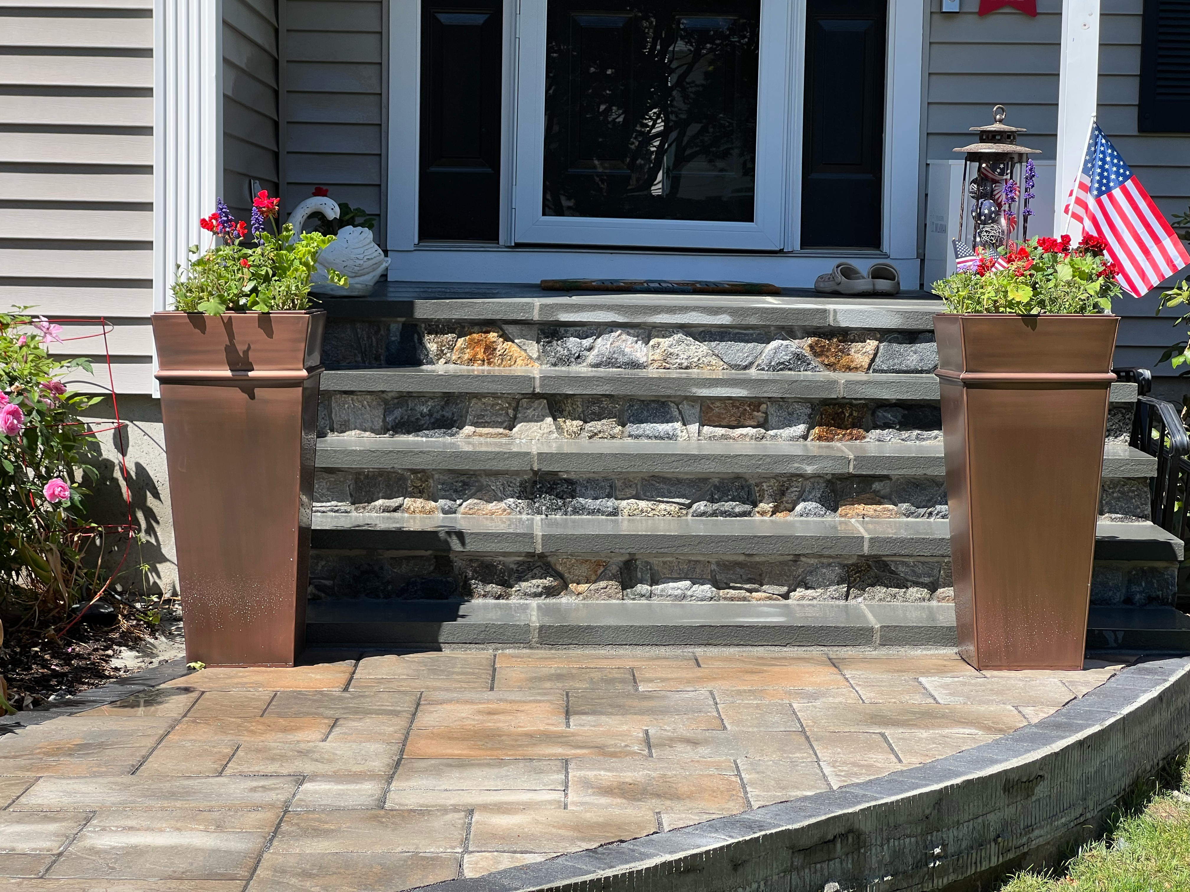 Natural stone veneer foundation wrapping with capstone, finished with river rock landscaping
